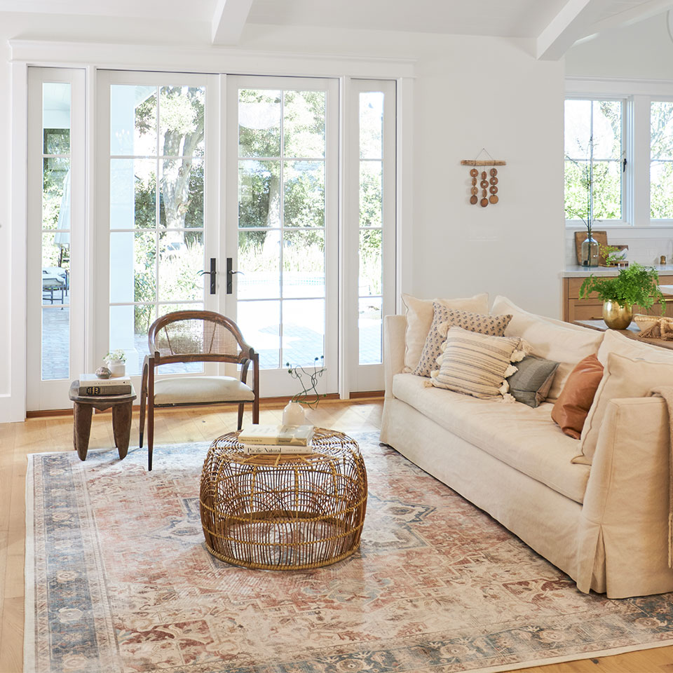 tan couch with coral and blue persian rug in living room