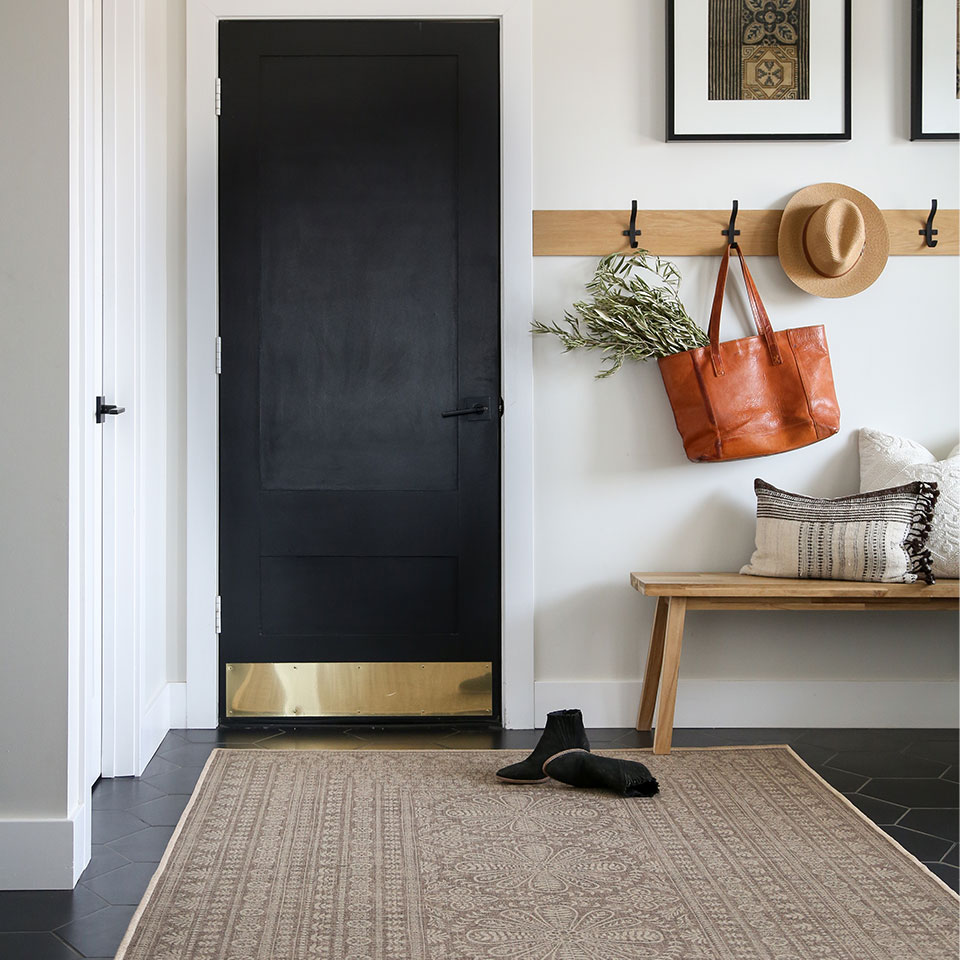 Re-jute rug with floral details in the mudroom with a black door