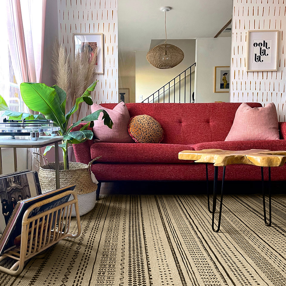 Striped Re-jute rug in an eclectic living room with red couch and pink pillows