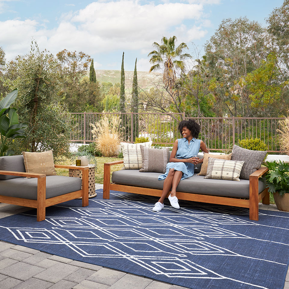 blue geometric outdoor rug on patio with grey furniture
