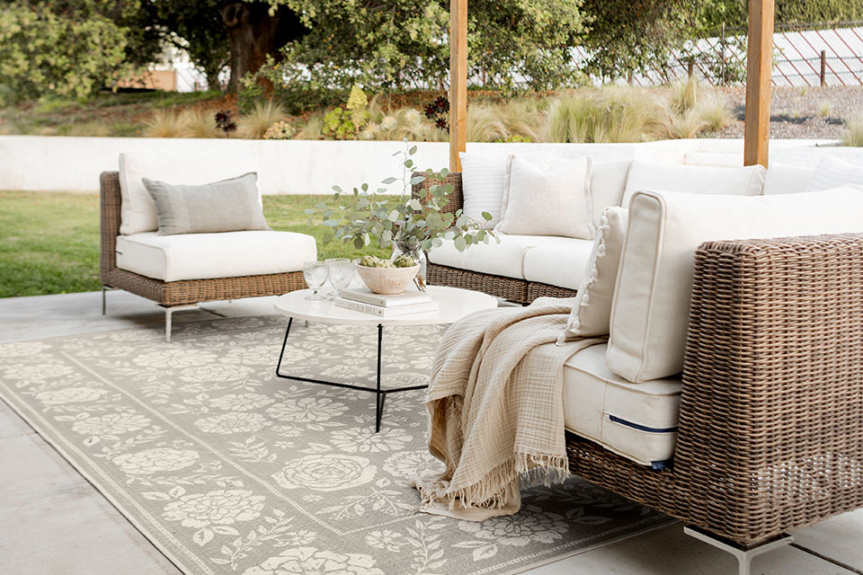 outdoor tan floral rug on patio with wicker furniture