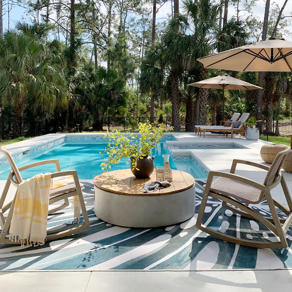 outdoor palm leaf rug by pool with chairs