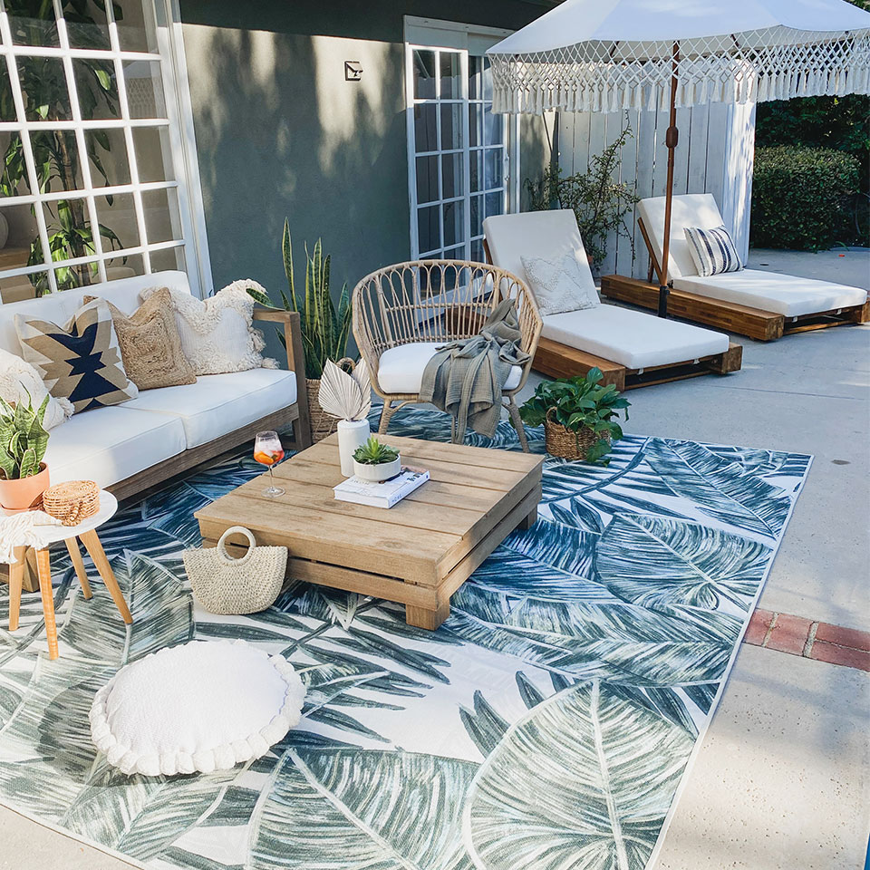 outdoor tropical palm leaf rug on patio with neutral furniture