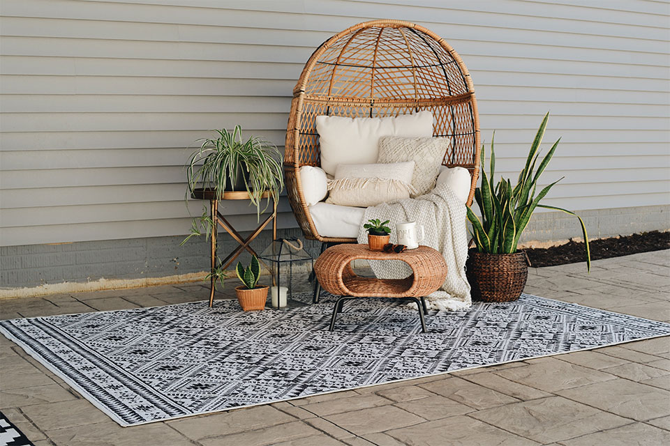small outdoor black and white boho rug with chair and plants