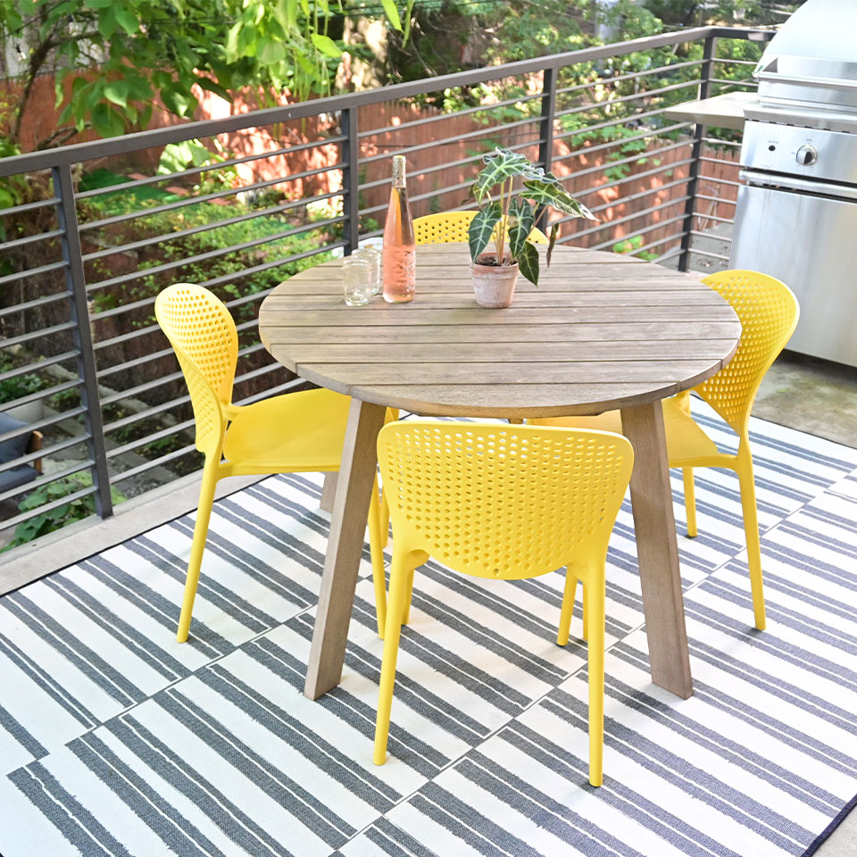 small outdoor striped rug on balcony with table and chairs