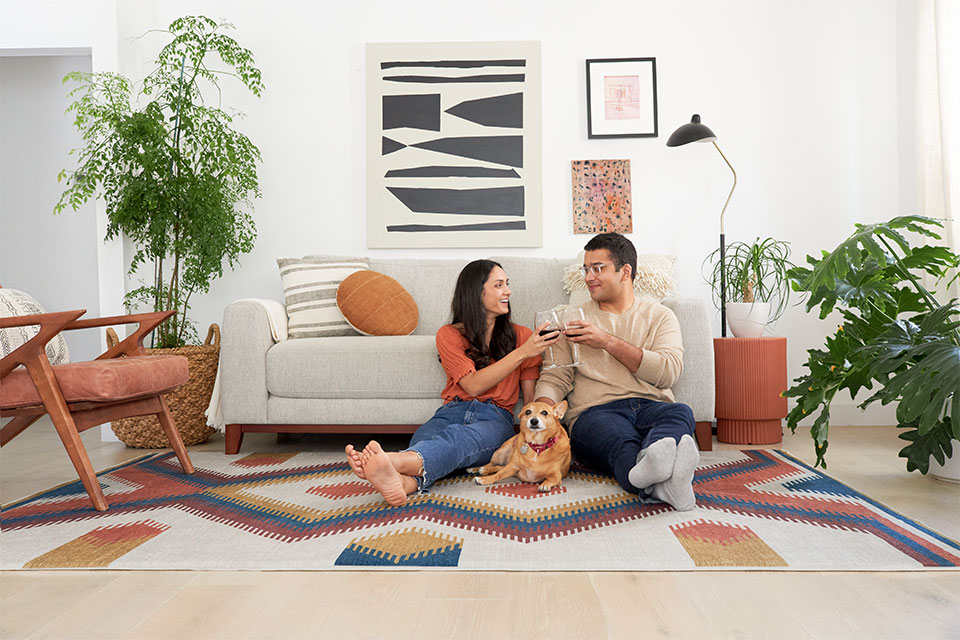 Couple and dog in the living room on a colorful geometric rug