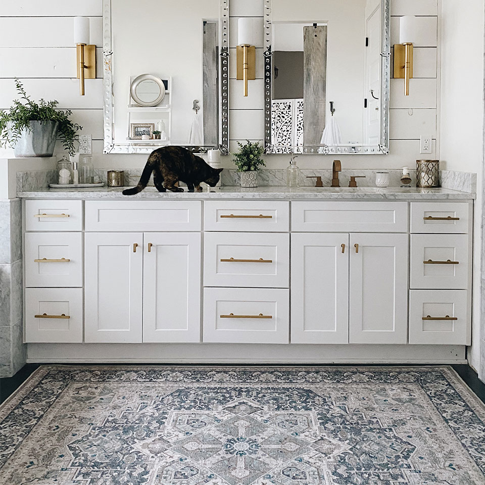 blue persian rug in bathroom with white cabinets